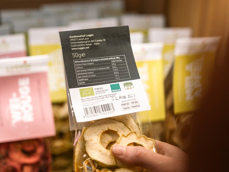 © IDM Südtirol/Hannes Unterhauser Pack of dried apples with the South Tyrol quality mark, taken by one person, with more slightly blurred packs of dried apples in the background. | © IDM Südtirol/Hannes Unterhauser