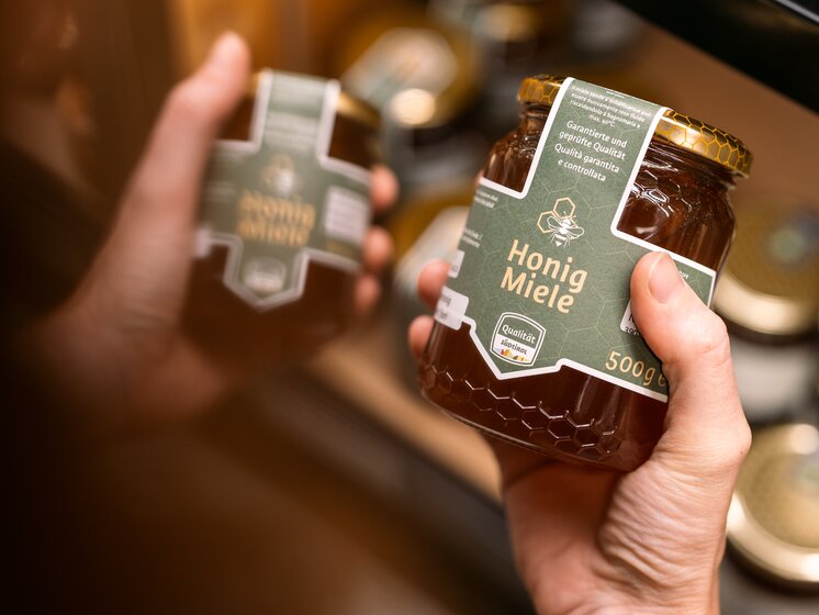 © IDM Südtirol/Hannes Unterhauser Two jars of honey, one in the foreground and one in the background, with the South Tyrol quality mark on the label, held by a person. | © IDM Südtirol/Hannes Unterhauser