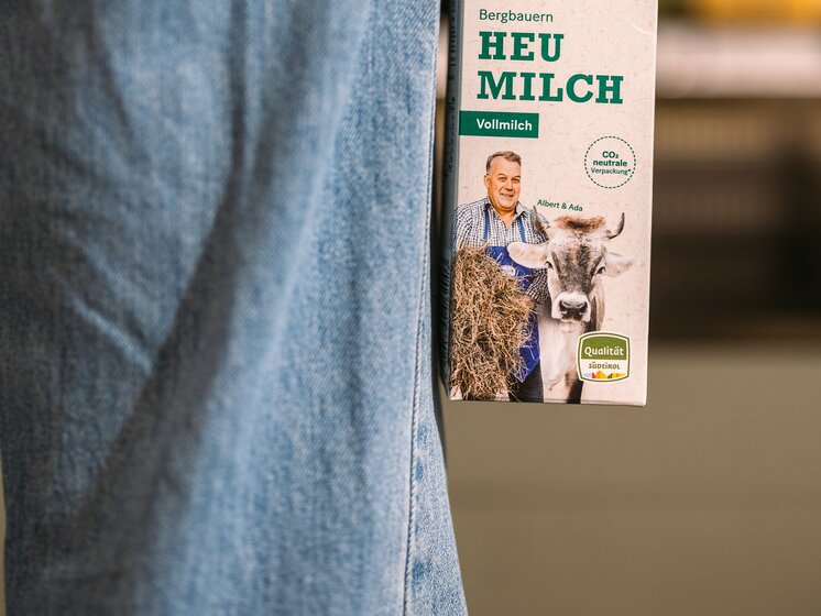 © IDM Südtirol/Hannes Unterhauser Whole milk Mila with the South Tyrol seal of quality, held on the side of a person wearing jeans. | © IDM Südtirol/Hannes Unterhauser
