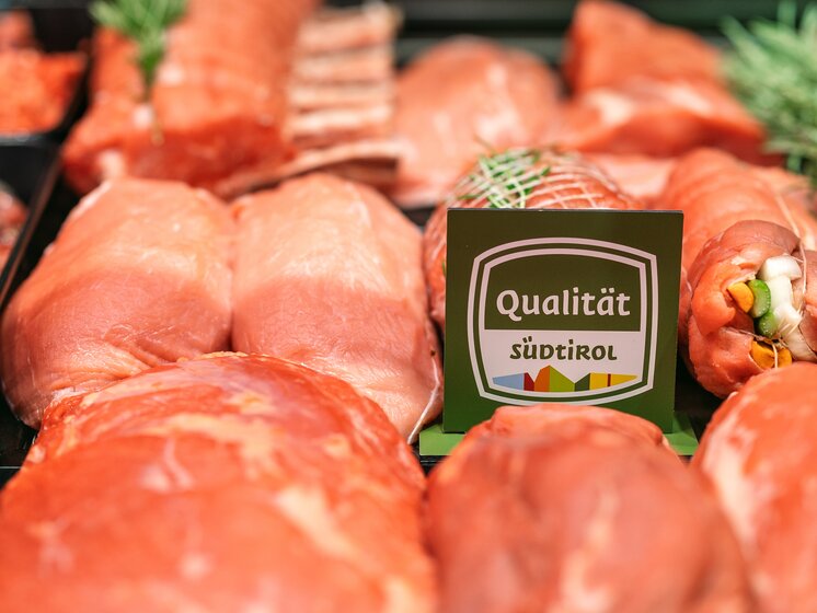 © IDM Südtirol/Hannes Unterhauser Frontal view of a meat counter with various cuts and preparations, featuring the Counter sign of the South Tyrol seal of quality slightly off-center. | © IDM Südtirol/Hannes Unterhauser